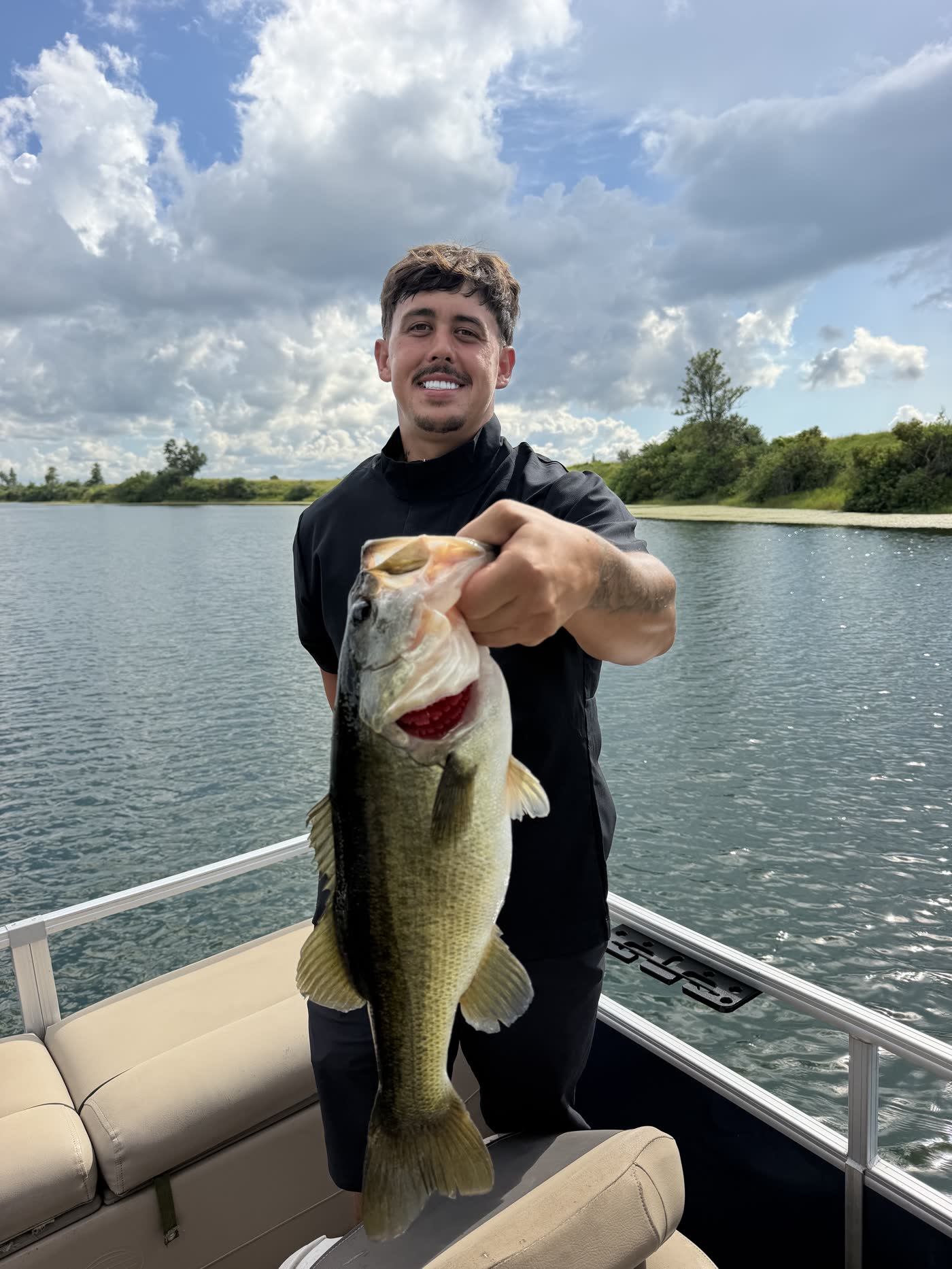 A player holding a largemouth bass on the lake at Streamsong