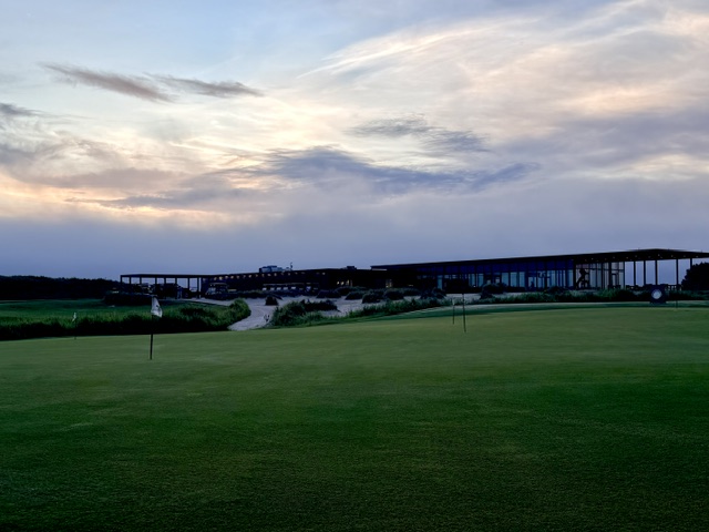 The putting green and clubhouse at dusk